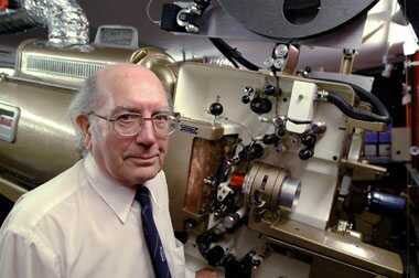 Projectionist standing in front of the brass projector